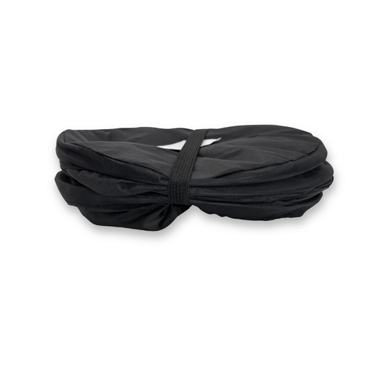 Compact folded black pop-up tabletop trash can secured with elastic band for easy packing in an artist kit.