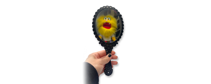 Ornate black handheld mirror for face painting and makeup with a playful reflection, perfect for revealing finished designs to clients.