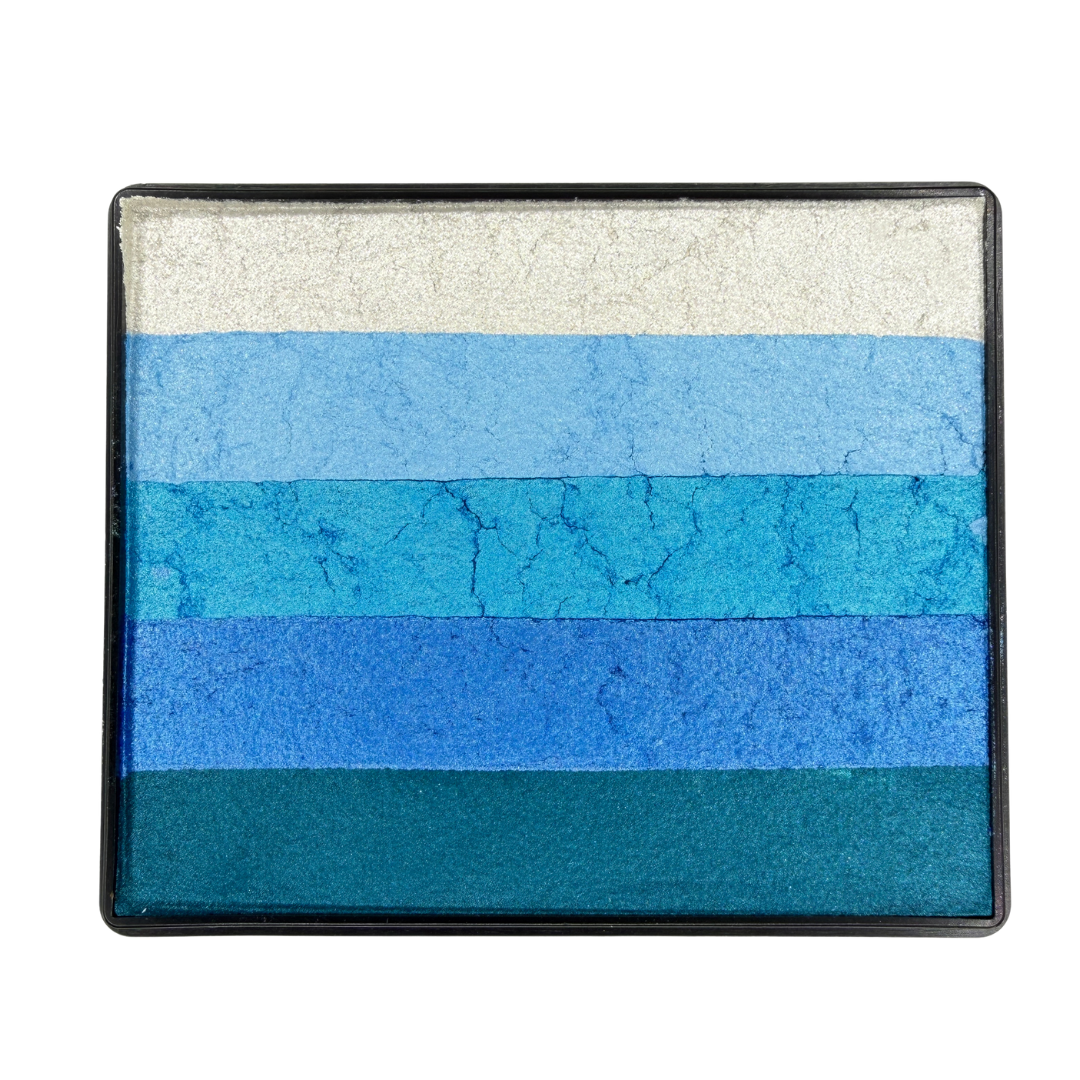 Shimmer Rainbow Cake face paint with layered stripes of pearl white, light blue, aqua blue, royal blue, and teal in a rectangular container.