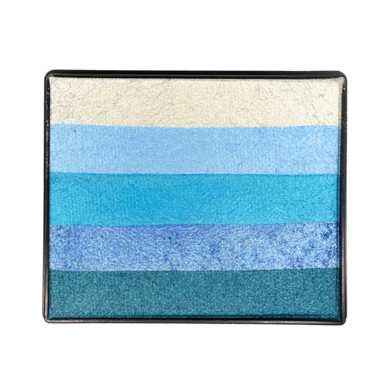 A square face paint pan with horizontal stripes of shimmering face paint in silver white, pale blue, light blue, bright cyan, periwinkle, and teal, set in a black case against a white background.