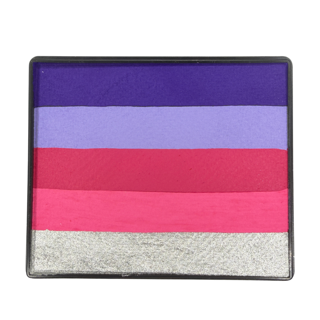Close-up of the Pink Potion Rainbow Cake one-stroke face paint in a rectangular black container, featuring five horizontal color bands: deep purple, lavender, magenta, hot pink, and metallic silver. The water-activated face paint is designed for fast one-stroke designs, fantasy face painting, floral designs, princess makeup, and colorful body art.