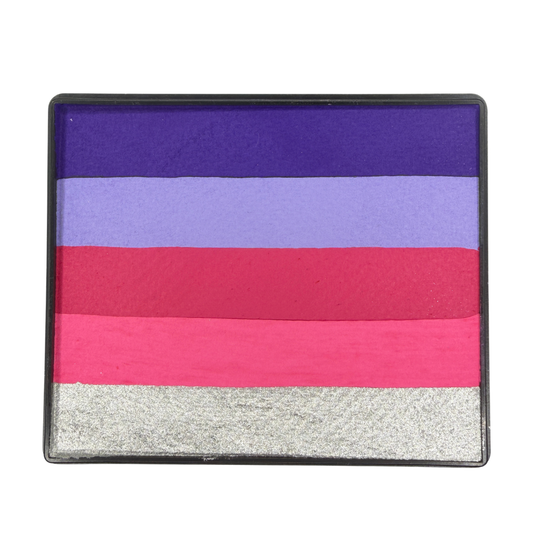 Close-up of the Pink Potion Rainbow Cake one-stroke face paint in a rectangular black container, featuring five horizontal color bands: deep purple, lavender, magenta, hot pink, and metallic silver. The water-activated face paint is designed for fast one-stroke designs, fantasy face painting, floral designs, princess makeup, and colorful body art.