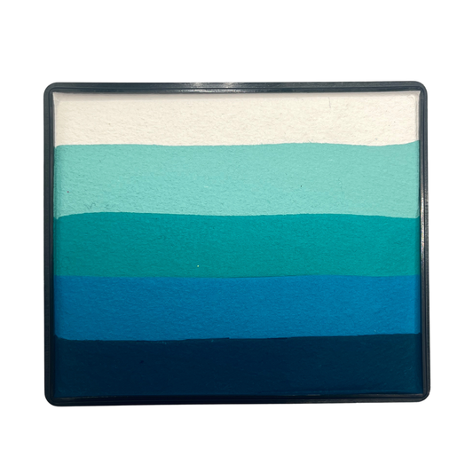 Blue and teal gradient Rainbow Cake face paint with layered stripes of white, mint, aqua, turquoise, bright blue, and deep navy tones in a rectangular container.
