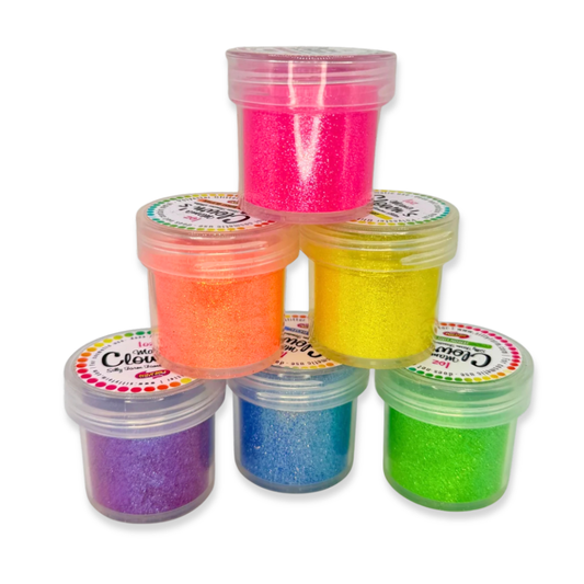 Six small clear plastic jars filled with glittery in assorted bright colors, arranged in a pyramid stack on a white background. The colors visible are pink, orange, yellow, blue, green, and purple.
