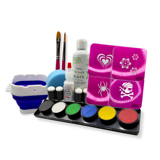 SillyFarm Face Painting Starter Kit featuring a six-color face paint palette in black, white, green, blue, yellow, and red, along with two paint brushes, a blue face painting sponge, four daubers, Silly Brush Bath cleaner, Mama Clown cosmetic glitter, and four reusable pink face painting stencils with heart, flower, spider, and pirate designs. All kit components are displayed together on a light background.