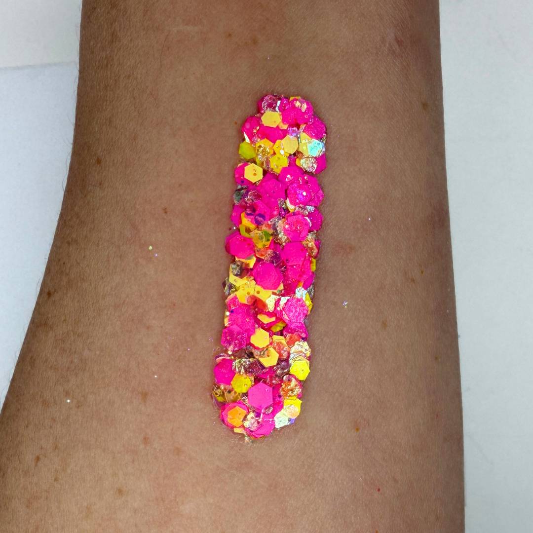 Swatch of SillyFarm Spirit Studio Sparkle Glitter Cream applied to skin, featuring bright pink, yellow, and iridescent cosmetic glitter in a smooth, water-resistant cream base. Limited edition glitter cream inspired by the signature SillyFarm colors.