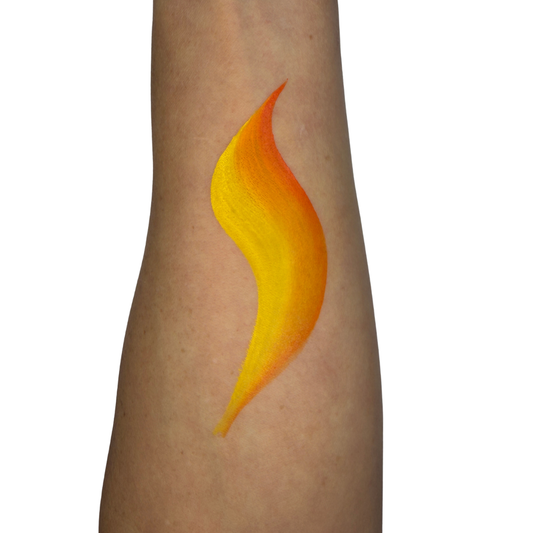 A yellow and orange swatch design shaped like an S, applied to a person's forearm, shown against a plain white background.