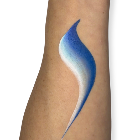A close-up of a person's forearm with a face paint brush stroke in a gradient of blues on the skin, against a plain white background. 